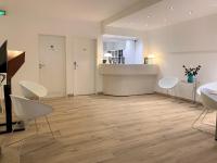 a room with white chairs and a counter and a kitchen at Hotel Francais in Luxembourg