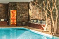 una piscina en una habitación con una pared de piedra en Clos l&#39;Abbe, Piscine &amp; Spa - Demeure de Prestige, en Ouville