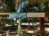 a sign on a beach with a palm tree at Pousada ZEN Cumuruxatiba in Cumuruxatiba
