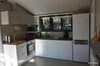 a kitchen with white cabinets and a white refrigerator at Chalet la lande in Ondres