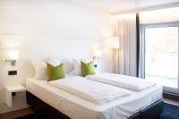 カウフボイレンにあるKF Hotel by WMM Hotelsの緑の枕が付いた大きな白いベッドのある寝室