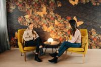 two women sitting in chairs in front of a wall at Hotel Sparre in Porvoo