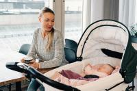 a woman sitting at a table with a baby in a stroller at Hotel Sparre in Porvoo