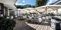 a restaurant with tables and chairs and umbrellas at Hotel Amélie in Brides-les-Bains