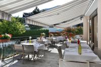 a restaurant with white tables and chairs on a patio at Hotel Amélie in Brides-les-Bains