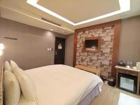a bedroom with a white bed and a tv at Jin Yong Quan Spa Hotspring Resort in Wanli District