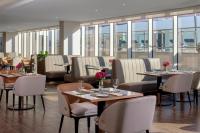 a restaurant with tables and chairs and windows at Avani Plus Palm View Dubai Hotel & Suites in Dubai