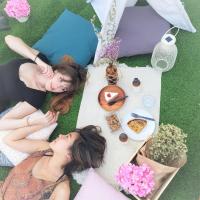 two women laying on the grass with food and flowers at T-Life Hostel in Longjing