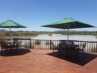una terraza con mesas, sillas y sombrillas en Crocodile Pools Resort, en Gaborone