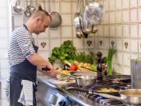 un hombre de pie en una cocina preparando comida en Ammergauer Zeitgeist, en Bad Kohlgrub