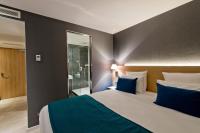 a bedroom with a large bed with blue pillows at Golden Tulip Sophia Antipolis - Hotel &amp; Spa in Valbonne
