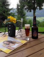 een fles bier en een boek op een houten tafel bij Landgasthof Heldenberg in Nenningen
