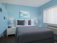 ein blaues Schlafzimmer mit einem großen Bett und einem Fenster in der Unterkunft South Beach Inn - Cocoa Beach in Cocoa Beach
