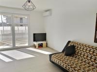 a living room with a couch and a tv at Appartement climatisé, moderne avec terrasses à 500m de la mer in Sérignan