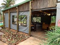 um deque coberto com uma mesa e cadeiras em Nabana Lodge em Hazyview