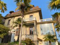 an old house with palm trees in front of it at Frankie’s House in Ghiffa