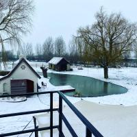 a house in the snow next to a pond at B&amp;B Leonie in Alveringem