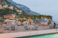 a group of people sitting around a table near the water at Hotel Poseidon in Positano