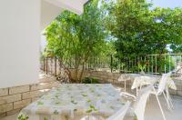 a patio with a table and chairs and trees at Rooms &amp; Apartments Barišić in Mlini
