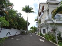 a parking lot in front of a building with a palm tree at Hôtel Résidence Le Phoenix in Saint-Pierre