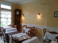 a dining room with tables and a clock on the wall at Hôtel Emilie in Royan