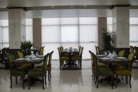 Un comedor con mesas y sillas y ventanas. en Fiori Hotel, en Erbil