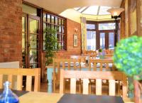 um restaurante com mesas e cadeiras de madeira e janelas em The George Inn & Millingbrook Lodge Ltd em Lydney