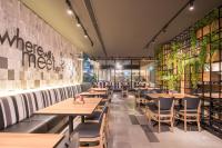 um restaurante com mesas de madeira, cadeiras e plantas em Holiday Inn Express Bangkok Sathorn by IHG em Banguecoque