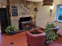 a living room with a stone fireplace with two chairs at Logis Hotel Le Relais De La Poste Restaurant Le Fil du Temps in Thury-Harcourt