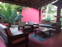 a patio with chairs and tables and a pink wall at Pousada ZEN Cumuruxatiba in Cumuruxatiba