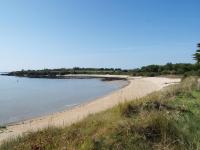 a beach with a group of people sitting on the sand at camping chez l&#39;habitant in Noyal-Muzillac