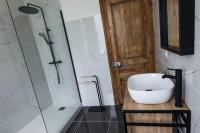 a bathroom with a sink and a shower with a glass door at La Villa de l&#39;Etoile jacuzzi privé chauffé à 37°C in Forges-les-Eaux