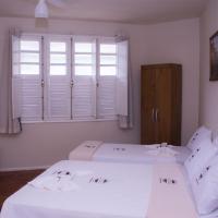two beds in a room with white walls and windows at Pousada Mama África in Conservatória