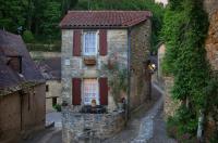 an old stone house with red shutters on a street at La Petite Maison in Beynac-et-Cazenac