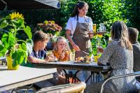 eine Gruppe von Menschen, die an einem Tisch im Garten sitzen in der Unterkunft De Krakeling in Zeist