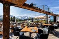 un restaurante con mesas y sillas y montañas de fondo en MY ALPENWELT Resort, en Königsleiten