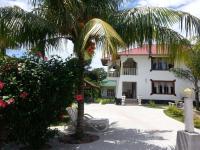 una palmera delante de un edificio en Zanboza Guesthouse, en La Digue