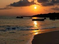 a sunset on the beach with a boat in the water at 海灘戀情 Beach Love 近沙灘-國旅卡特約商店 in Eluan