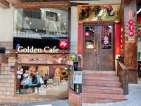 a store front of a golden cafe with a man in the window at Chiu Chunt Dint B&amp;B in Jiufen