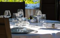 a table with wine glasses and plates on it at Au Moulin de La Gorce in La Roche-lʼAbeille