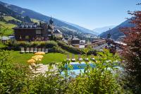 a resort with a pool with umbrellas and chairs at Hotel Saalbacher Hof in Saalbach-Hinterglemm