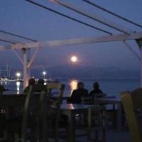 Un grupo de personas sentadas en una mesa mirando la luna. en Fisilanis Beachfront Hotel, en Logaras