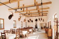 un comedor con mesas, sillas y astas en la pared en GLASHÜTTE Kisújbánya Vadászház, en Hosszúhétény-Szőlőhegy