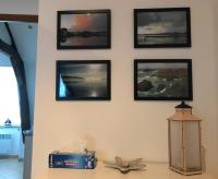 a wall with four pictures on a wall with a lamp at Appartement de charme rue du Château in Auray