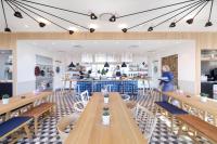 a restaurant with wooden tables and chairs and a counter at Zoku Copenhagen in Copenhagen