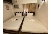 Dos camas en una habitación pequeña con sábanas blancas. en E Relaxed Haven Transient House, en Manila