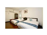 a hotel room with two beds with white sheets at Phoenix Walkway Homestay in Taitung City