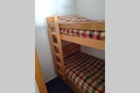 a bunk bed with a plaid blanket on it at Studio 4pers vue piste in Le Corbier