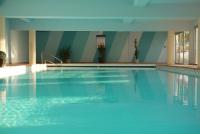 a swimming pool with blue water in a building at Hotel Europa in Quiberon
