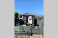 a tiny house with a green fence at Trevone Luxury Shepherds hut close to the beach in Saint Merryn
